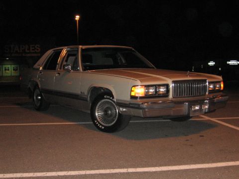 1988 Mercury Grand Marquis - This sedan is parked in a lot at night, with a Staples store visible in the background.