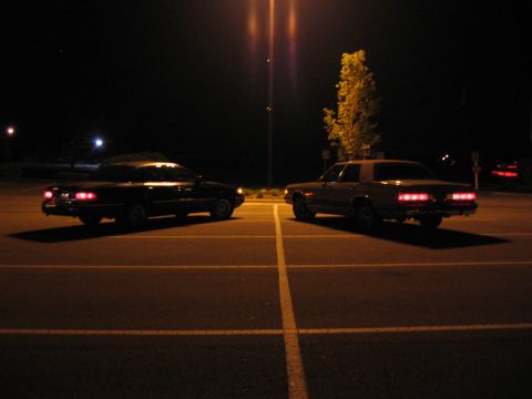 1988 Mercury Grand Marquis - Two 1988 Mercury Grand Marquis sedans are parked in a lot at night.