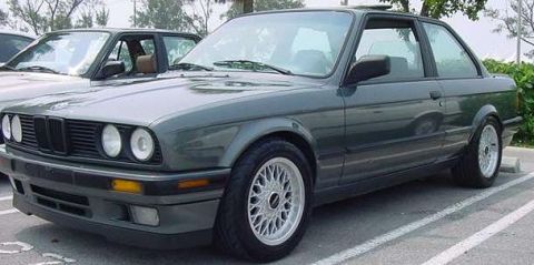 1989 BMW 3 Series - A 1989 BMW 3 Series coupe is parked in a lot, with another vehicle partially visible behind it.