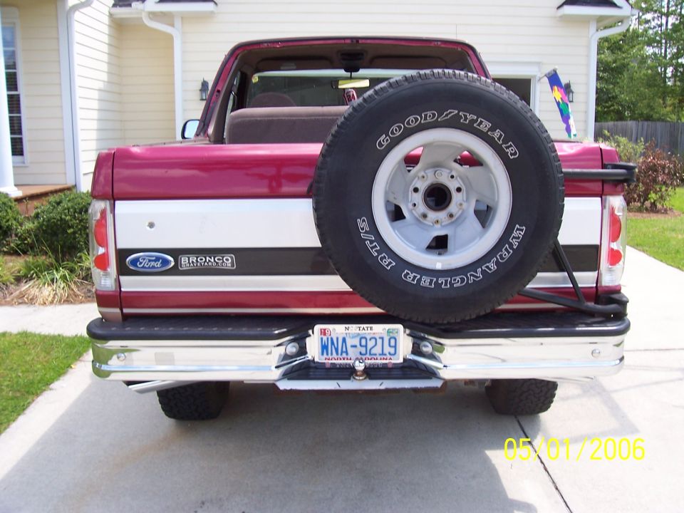 Rear view of a red and white Ford Bronco with a spare tire mounted on the back. License plate reads WNA-9219