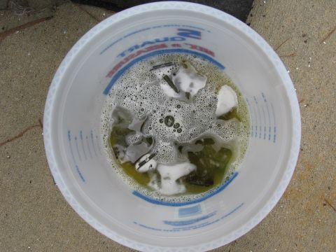 1973 Ford Ranchero - Metal parts are submerged in a bucket filled with soapy water and bubbles.