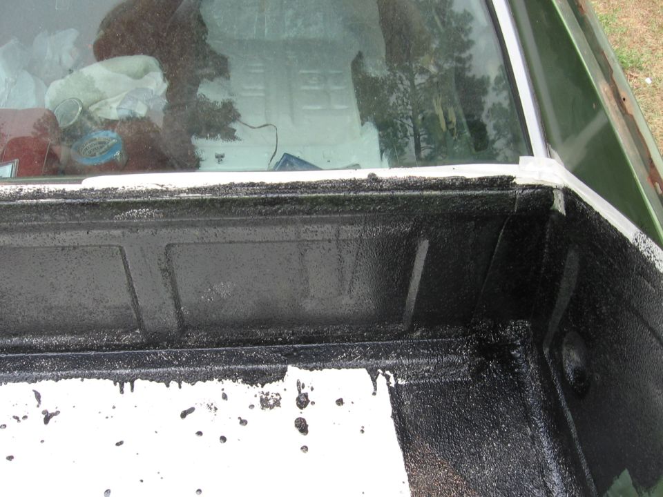 Truck bed liner with black spray-on coating and white paint drips, viewed from above