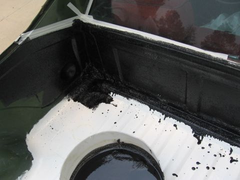 1973 Ford Ranchero - Close-up of a vehicle bedliner corner where black paint is being applied over white primer.