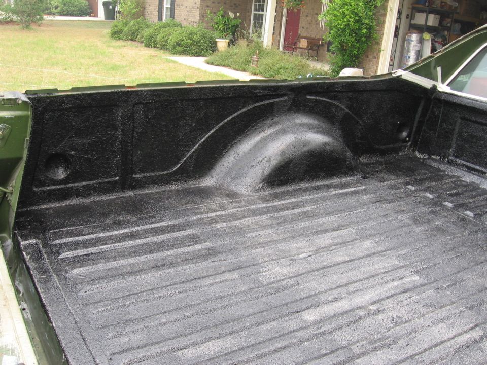 Green 1973 Ford Ranchero bed liner with black spray-on coating, showing ribbed floor and wheel well