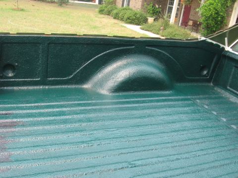 1973 Ford Ranchero - The interior of a truck bed shows a freshly applied green bed liner with a textured finish.