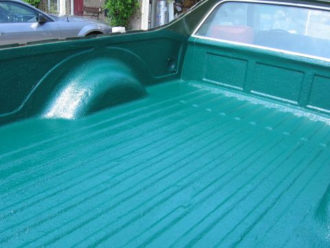 1973 Ford Ranchero - The bedliner of a 1973 Ford Ranchero is painted a vibrant green, with visible ribbed texture and a wheel well.