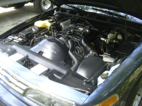 1996 Ford Crown Victoria - Engine bay detail of a 1996 Ford Crown Victoria, with another vehicle visible in the background.