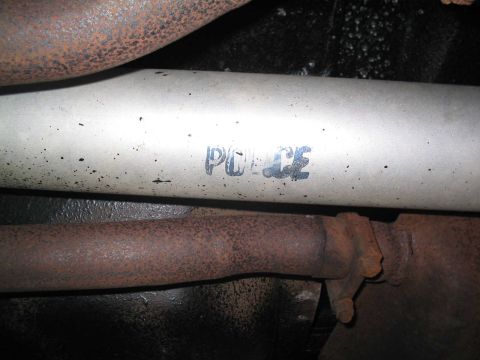 2001 Ford Crown Victoria - Close-up of a vehicle's exhaust system, revealing a stencil marking that reads "POLICE".