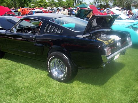 1972 Ford Ranchero - A black coupe with louvers on its rear quarter windows is displayed at an outdoor car show.