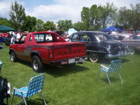 1972 Ford Ranchero - A red Dodge pickup truck and a black sedan are parked on a grassy field at an outdoor car show.