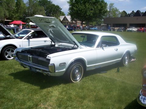 1972 Ford Ranchero - White 1968 Mercury Cougar XR-7 at a car show, hood open, with another vehicle beside it.
