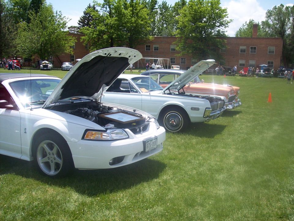 White convertible with hood open, showing engine and a framed picture