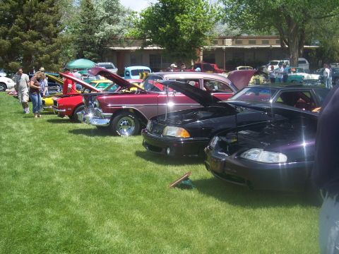 1972 Ford Ranchero - Cars are displayed on a grassy field with people milling around and buildings in the background.