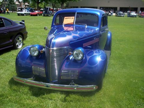 1972 Ford Ranchero - A custom blue hot rod with flame graphics is displayed on a grassy field at a car show.