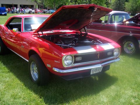 1972 Ford Ranchero - A red 1967 Chevrolet Camaro RS with racing stripes is displayed with its hood open at a car show.