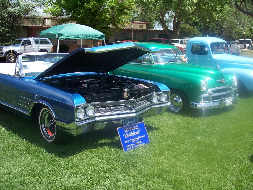 Blue 1965 Buick Wildcat convertible with hood open, parked on grass