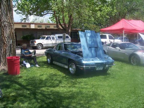 1972 Ford Ranchero - A man sits in a chair next to a classic blue car with its hood open at an outdoor car show.
