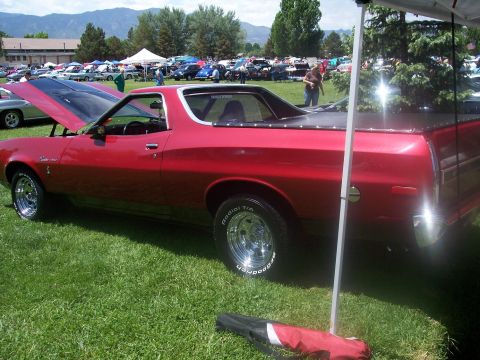 1972 Ford Ranchero - A red 1972 Ford Ranchero is displayed at a car show with other vehicles in the background.