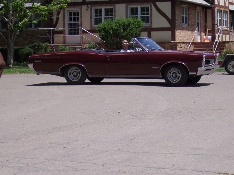1972 Ford Ranchero - A maroon convertible is parked in front of a building with a person driving.