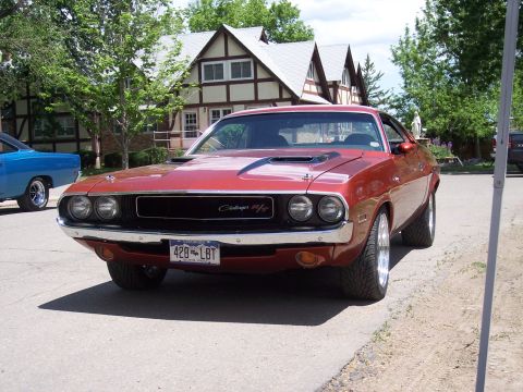 1972 Ford Ranchero - A red Dodge Challenger with a Challenger R/T badge is parked on a street, with another blue car visible to the left.