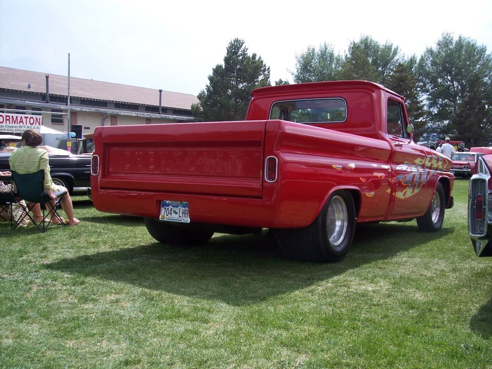 Red 1960 Chevrolet C10 pickup truck with flame decals on the side, parked on grass