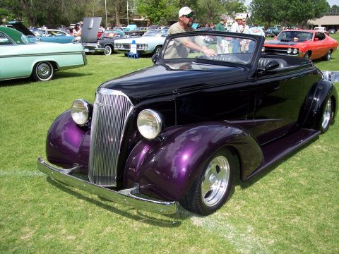 1972 Ford Ranchero - A custom hot rod convertible with a distinctive grille and purple fenders is displayed at a car show.