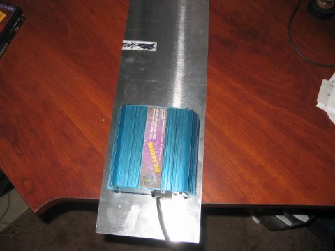 1991 Ford Bronco - A blue electronic device with fins is attached to a metal plate on a wooden surface.