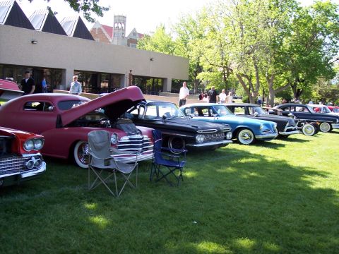1972 Ford Ranchero - Several vintage automobiles are displayed on a grassy area in front of a building.