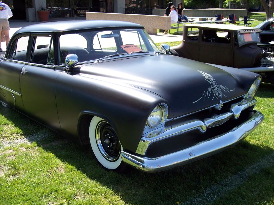 Black matte custom sedan with whitewall tires, chrome grille, and pinstriping on the hood