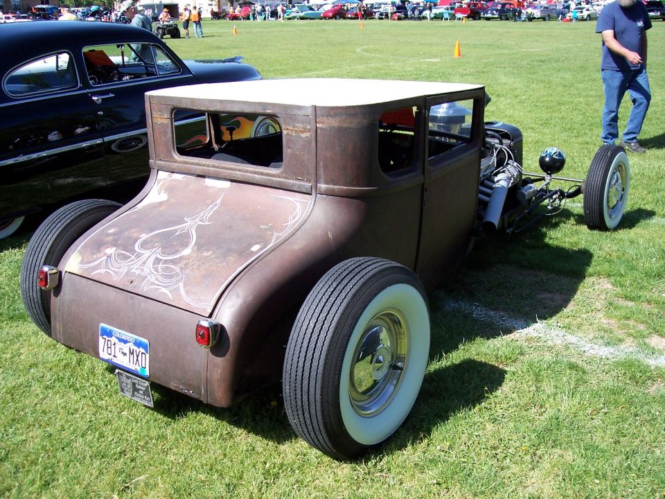 Rusty hot rod coupe with white wall tires and pinstriping on the trunk