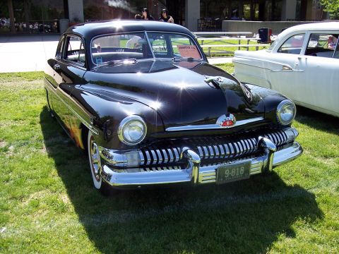 1972 Ford Ranchero - A classic black 1950 Mercury is displayed at an outdoor car show with a white car nearby.