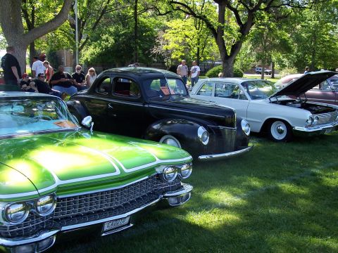 1972 Ford Ranchero - Several classic cars are displayed on a grassy lawn under the shade of trees at an outdoor event.