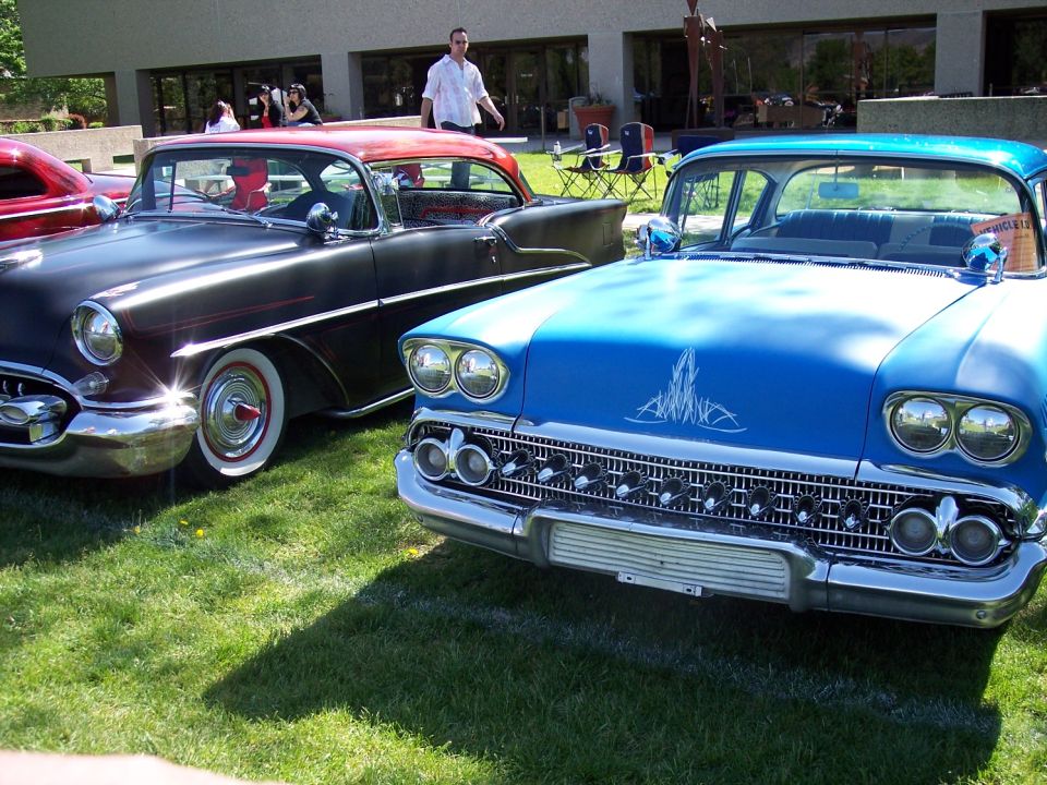 Blue 1958 car with chrome grille, dual headlights, and pinstriping on the hood