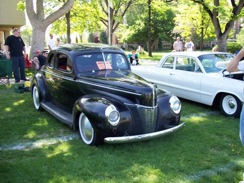1972 Ford Ranchero - A black 1940 Ford Coupe is parked on the grass at an outdoor car show next to a white vehicle.