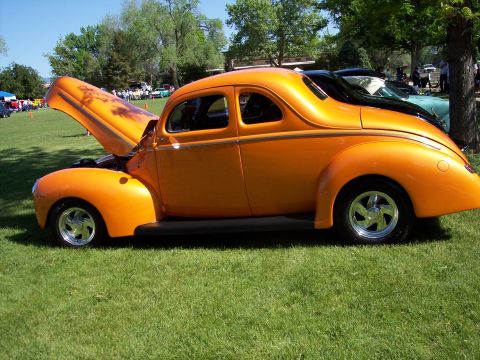 1972 Ford Ranchero - An orange hot rod coupe with its hood open is displayed at an outdoor car show.