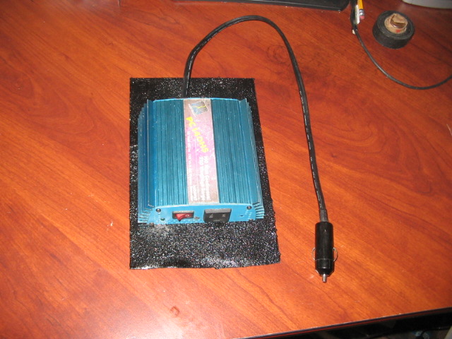 Blue power inverter with a car adapter plug on a wooden surface