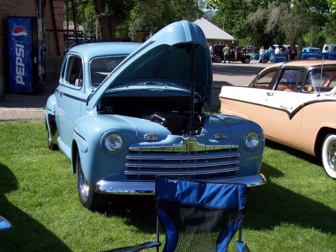 1972 Ford Ranchero - A light blue 1949 Ford coupe is displayed with its hood open at a car show, with another classic car visible to the right.