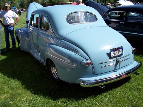 1972 Ford Ranchero - A light blue coupe with its hood open sits on a grassy field next to other vehicles.