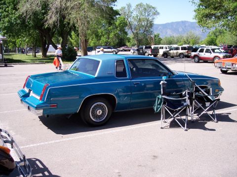 1972 Ford Ranchero - A blue coupe is parked in a lot, with folding chairs set up in front of it. Mountains are visible in the distance.
