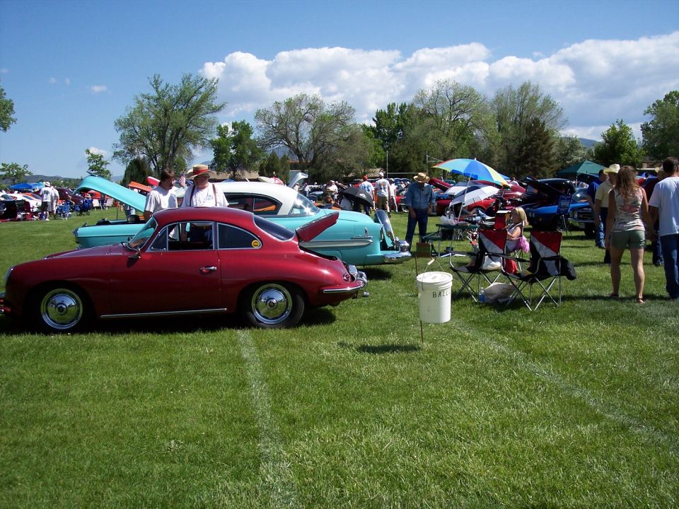 Red coupe and turquoise sedan with open trunk at outdoor car show
