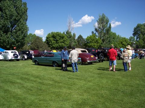 1972 Ford Ranchero - Attendees observe a collection of vintage automobiles displayed outdoors on a sunny day.