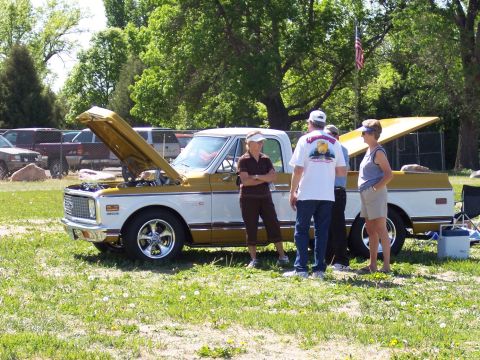 1972 Ford Ranchero - A gold and white pickup truck is displayed with its hood open at an outdoor event.