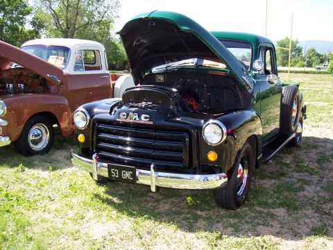 1972 Ford Ranchero - A black 1953 GMC truck is parked next to another truck with its hood open.