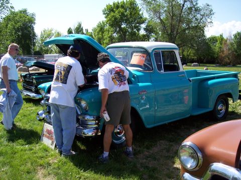 1972 Ford Ranchero - People examine a turquoise 1955 Chevrolet pickup truck at a car show, with another vehicle visible.
