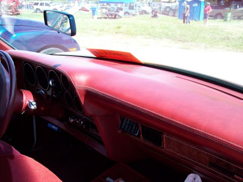 1972 Ford Ranchero - Interior view of a red dashboard with an orange tag. Multiple vehicles are visible in the background at an outdoor event.