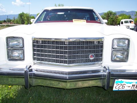 1972 Ford Ranchero - A white 1977-1979 Ford Thunderbird is parked on grass, with mountains in the distance and another vehicle behind it.