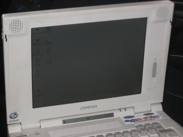 White Compaq laptop with screen on, showing desktop icons and "Intel Inside Pentium" sticker