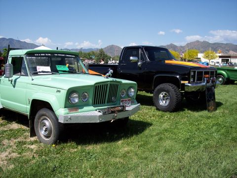 1972 Ford Ranchero - A green Jeep pickup truck is parked on a grassy field with mountains in the background.