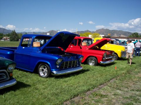 1972 Ford Ranchero - A line of colorful classic pickup trucks are displayed with their hoods open at an outdoor car show.