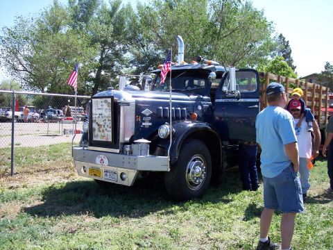 1972 Ford Ranchero - A dark blue semi-truck is parked on grass, with people gathered around it at an outdoor event.
